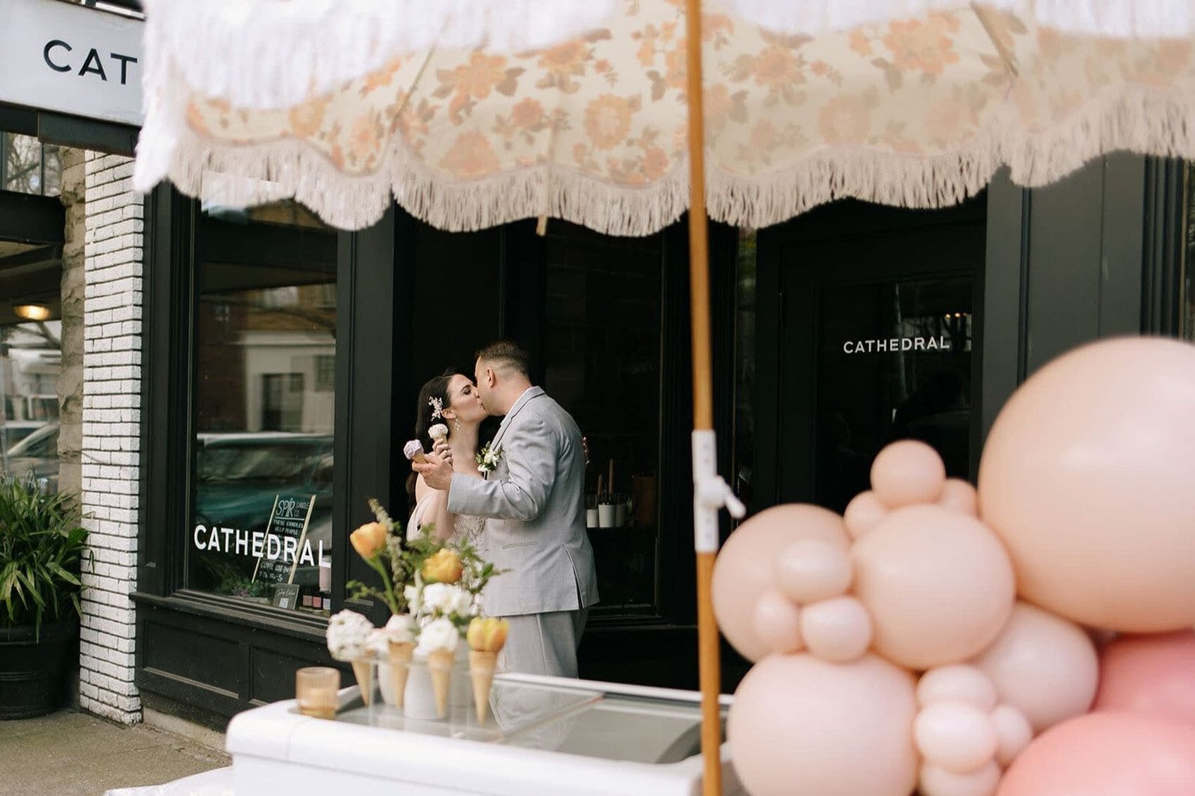 Newlyweds celebrating outside stylish Cincinnati storefront with pink balloons
