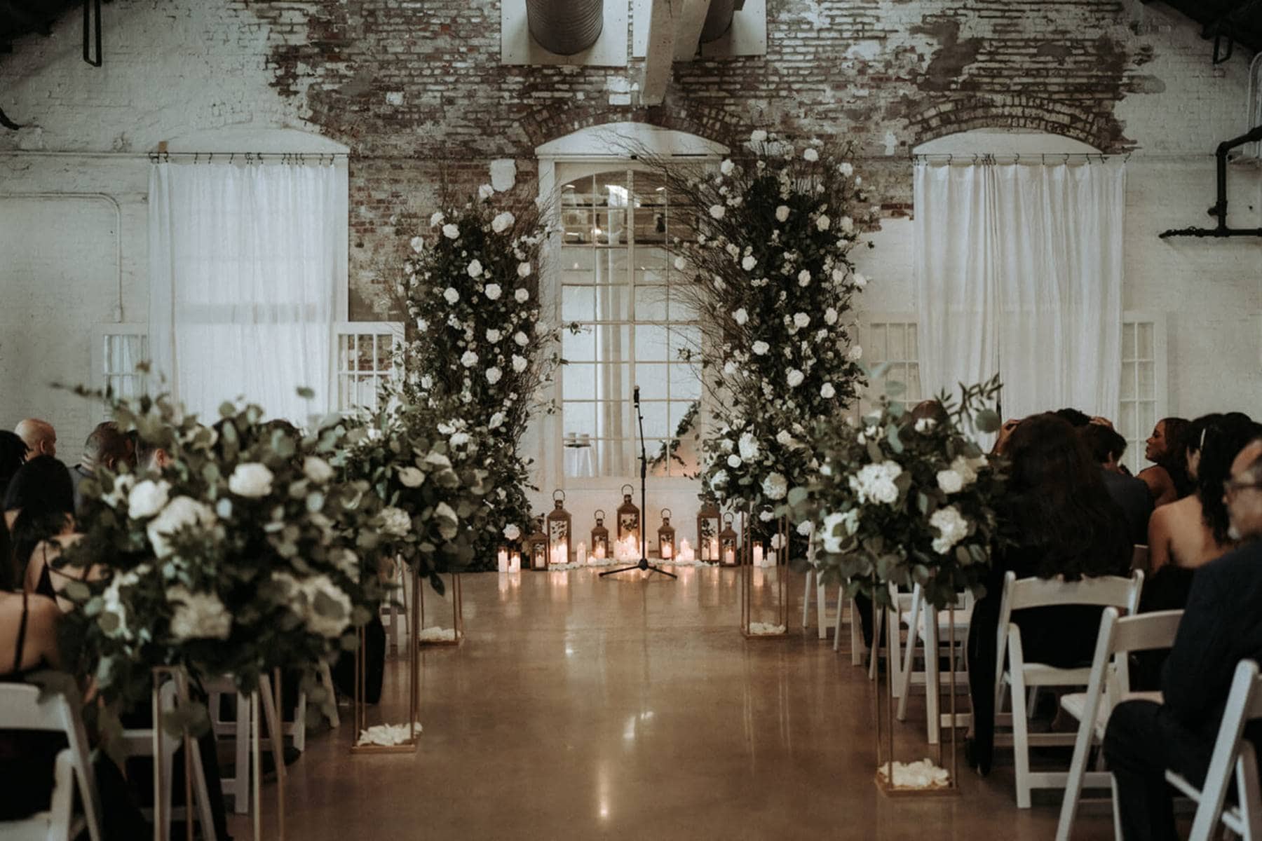 Indoor Cincinnati ceremony setup featuring floral arch and exposed brick