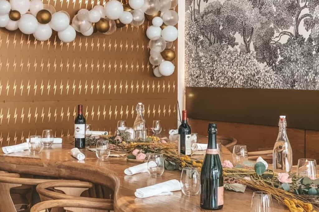 a decorated table with wine and balloons at an event