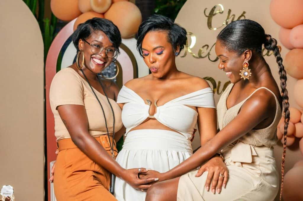 women touching friend's pregnant belly